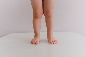 Low section of baby boy in diaper standing isolated on blue background