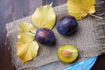 Purple fresh raw plums with autumn leaves