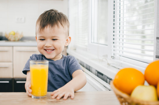 The Child In The Kitchen, Drinking Orange Juice, Close On Background Of Fruits