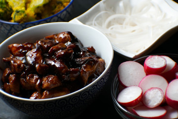 Pieces of teriyaki chicken, rice vermicelli and radish on the table close-up. Asian cuisine