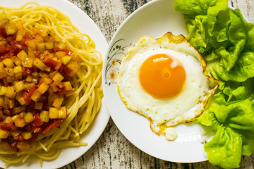 Spaghetti pasta with fried eggs on wood background