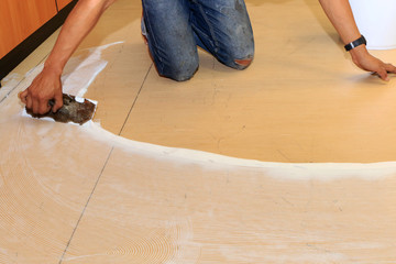 Craftman hands glue the floor for laying a floor. Repair and renovation interior office building.