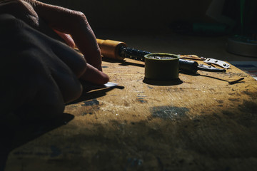 Working with a hot metal soldering iron at home under the spotlight and smoke that comes from...