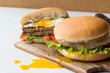 Half Cut Hamburger with Egg, Tomatoes and Lettuce on Wooden Surface.