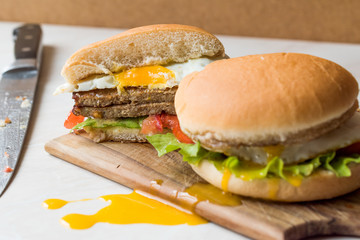Half Cut Hamburger with Egg, Tomatoes and Lettuce on Wooden Surface.