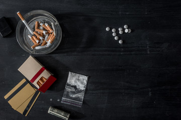 top view of mdma pills, cocaine and cigarettes on black wooden surface