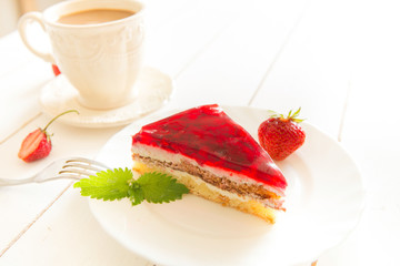 Cup of coffee with strawberry cake on a white wooden table