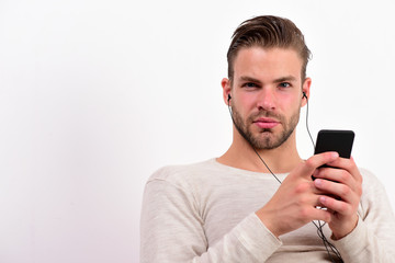 Guy with beard holds MP3 player and wears earphones