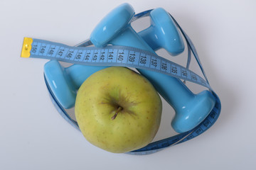 Dumbbells in bright green color, measure tape and fruit