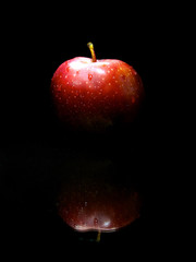 Sweet red apple on black background with reflection