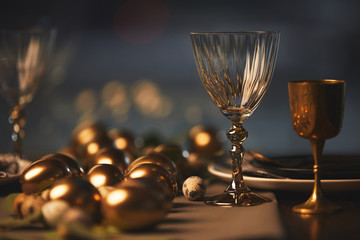 Golden easter eggs and glasses on festive table