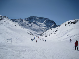 Fototapeta na wymiar People of all ages ski down a shallow sloping valley in the three valleys ski region of France