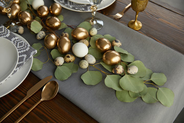 golden easter eggs on green leaves on festive table