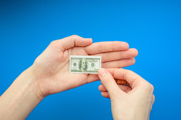 Woman's hand holding small banknote of 100 US dollar