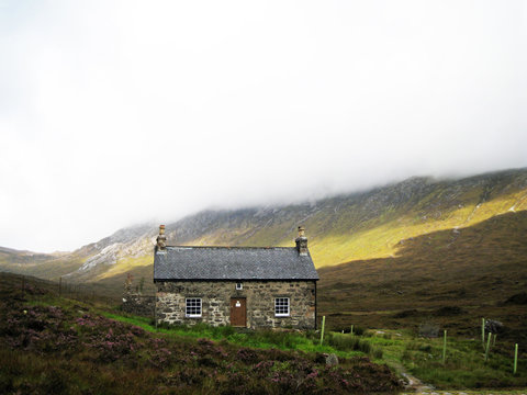 A welcoming looking Bothy on a typical highlands day with low cloud with some sunshine breaking through, in Torridon, Scotland