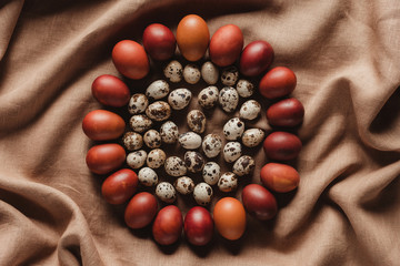 food composition of easter quail eggs in circle of chicken eggs on linen tablecloth