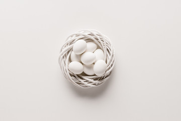 White chicken eggs in easter wreath on white background