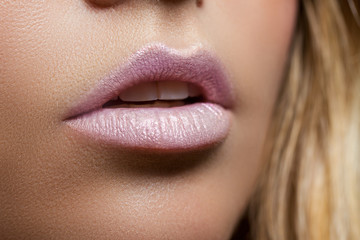 Ajar female mouth closeup. Delicate pink lips. Perfect skin. Pearl lipstick