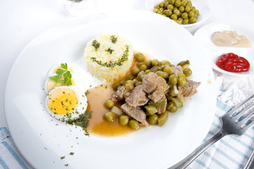 Delicious dinner beef Stroganov with peas and sterilized cucumber