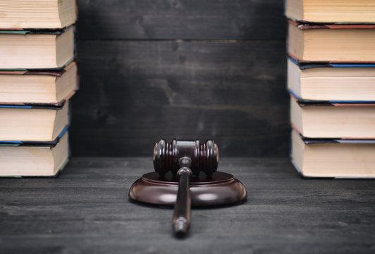 Judge Gavel and law books on a black wooden background, law library concept.