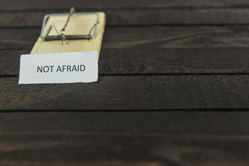 blured wooden mouse trap with the word: Not afraid.