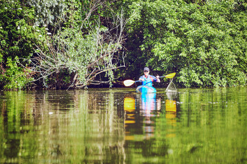  Man paddling a kayak on summer day.