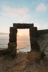 Stone gate towards the ocean with sunrise view.