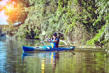 Fototapeta na wymiar Man paddling a kayak on summer day.