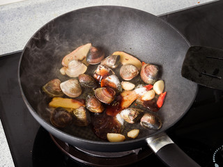 Stir-frying Ginger and clams at high heat to bring forth the savory aroma with sesame oil in recipe