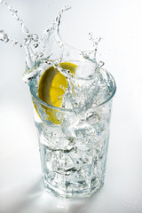 Lemon splashing on a glass against a white background