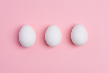 Happy Easter concept. White eggs on pink background close up. Flat lay. Minimal concept. Top view. Design, visual art.