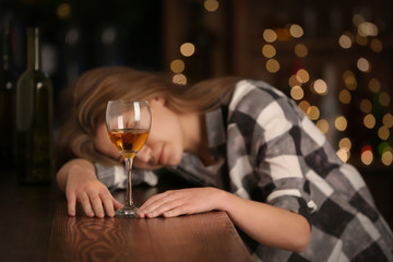 Unconscious drunk woman with glass of wine in bar. Alcoholism problem
