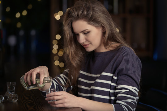 Young woman pouring drink into glass at bar. Alcoholism problem