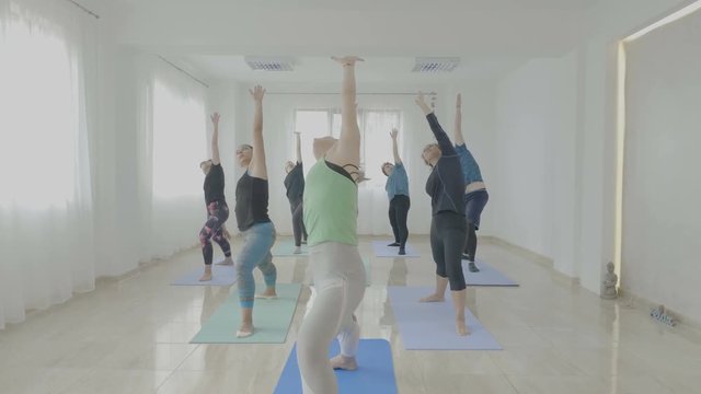 Women learning warrior pose during a yoga class as therapy to recover after treatment