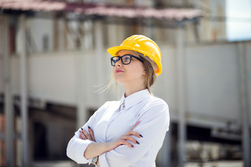 Portrait of a young female engineer wearing goggles and a safety helmet at work site