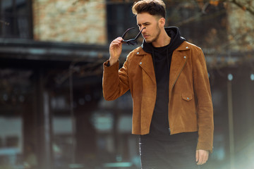 Model looking man stand on the city street with cars background, look on his watch and around