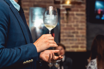 man in a blue suit holds glass of white wine