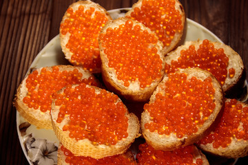 Naklejka na ściany i meble Sandwiches with butter and red caviar on wooden table