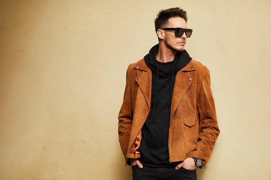 Model Looking Man Stand Near The Wall And Hold His Glasses Towards The Sun Shine