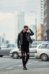 Model looking man stand on the city street with cars background, look on his watch and around