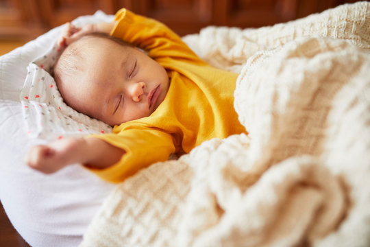 Newborn baby sleeping under knitted blanket