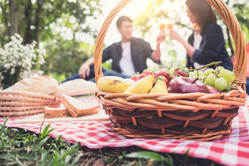 Couple in love drink a orange juice and fruits on summer picnic, leisure, holidays, eating, people and relaxation concept