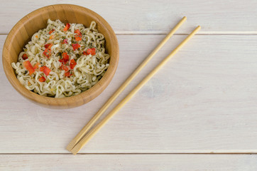 Instant noodles with on wooden bowl and chopsticks on white background with copy space. Typical Asian street food concept.