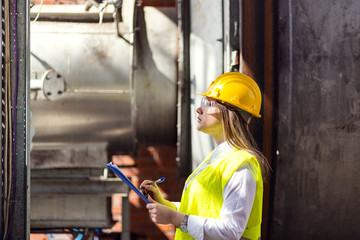 Young female engineer using clipboard.Female quality inspector at factory