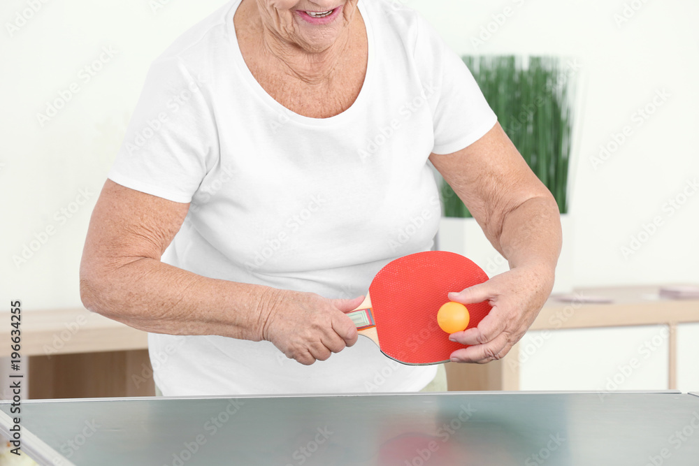 Wall mural Senior woman playing table tennis indoors