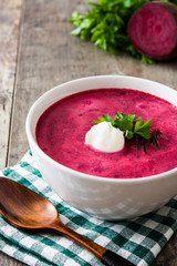 Beet soup in white bowl on wooden table