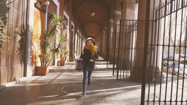 portrait of young woman runs under the arches in the city