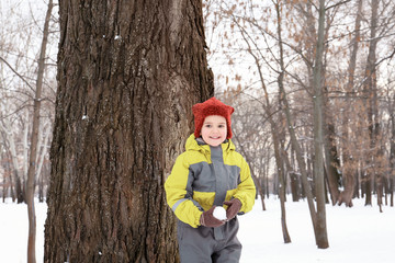 Cute boy playing in snowy park on winter vacation