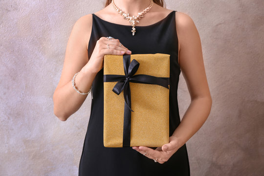 Young woman holding gift box on light background