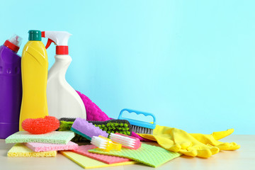 Set of cleaning supplies on table against color background